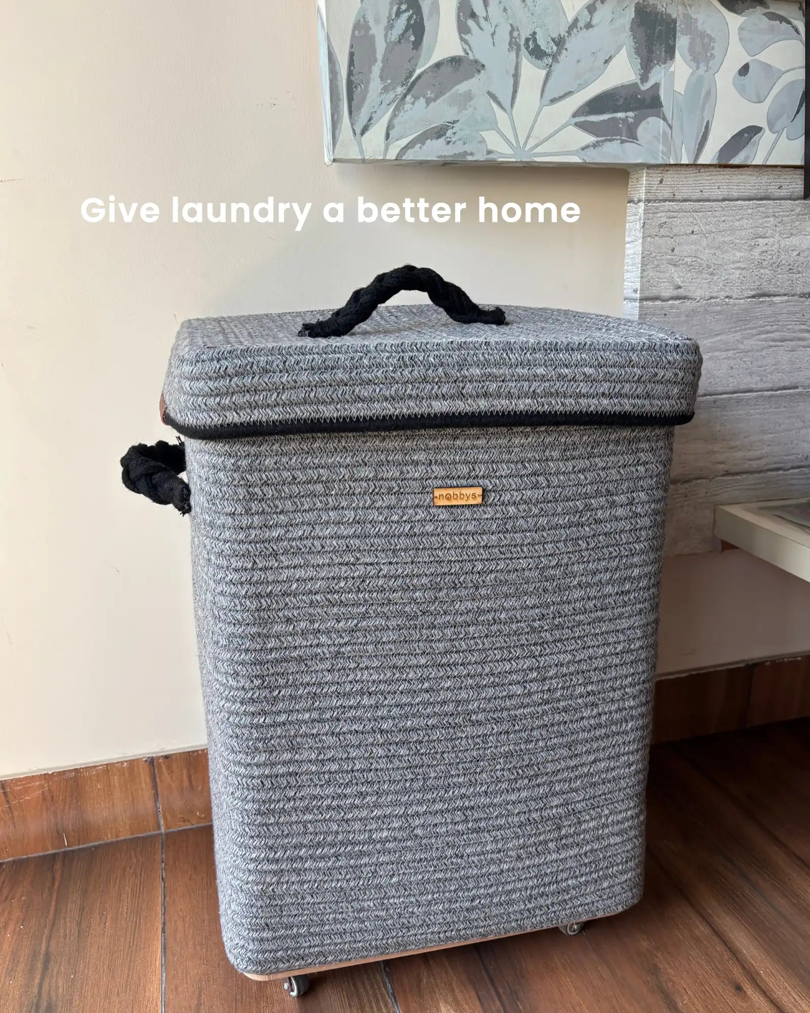 GrEy laundry basket with a handle on a wooden floor.