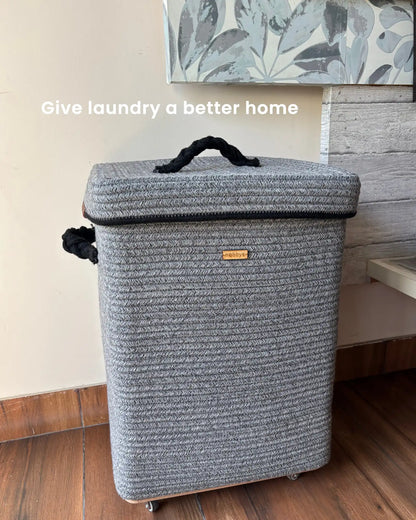 GrEy laundry basket with a handle on a wooden floor.